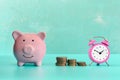 Between the piggy bank and a small pink alarm clock, three stacks of coins are in order. The symbol of the growth of Royalty Free Stock Photo