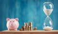 Piggy bank with stacked coins and hourglass Royalty Free Stock Photo