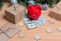 A piggy bank standing on cash dollars on a table with gift boxes, snowflakes and Christmas fir branches. New year saving