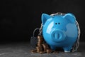 Piggy bank with steel chain, padlock and coins on grey stone table against black background, space for text. Money safety Royalty Free Stock Photo