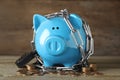 Piggy bank with steel chain, padlock and coins on table. Money safety concept Royalty Free Stock Photo