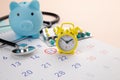 Piggy bank, stethoscope, alarm clock and calendar on a table, schedule to check up healthy concept Royalty Free Stock Photo