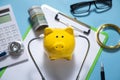 Piggy bank with stethoscope, money and calculator on the blue background Royalty Free Stock Photo