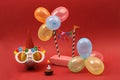 Piggy bank with sunglasses Happy birthday, party hat and multicolored party balloons on red background Royalty Free Stock Photo