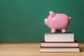 Piggy bank on top of books with chalkboard Royalty Free Stock Photo