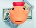 Piggy bank on top of a wad of hundred dollar bills in a white background Royalty Free Stock Photo