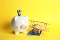 Piggy bank with toy airplane and passport on color background. Travel Royalty Free Stock Photo