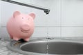 Piggy bank and water pouring from tap. Water saving concept Royalty Free Stock Photo