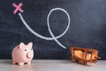 A piggy bank and a wooden biplane airplane on a chalk board background. Chalk drawing of loops and a red cross