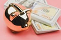 Piggy banks and a house model with banknotes US dollars for saving to buy a house on pink background.