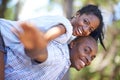 Piggyback, portrait or happy black couple in park to relax or bond on holiday vacation together to travel. Romantic