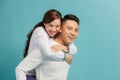 Piggyback ride. Young man carrying girlfriend on his back, blue background with copy space Royalty Free Stock Photo