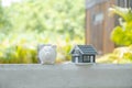 piggybank and the home model stands in front of home background, Saving money for buy real Estate concept