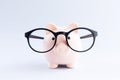 Piggybank for money wear glasses on gray table close-up