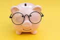 Piggybank wearing glasses on yellow background using as saving money, investment, budget, financial concept