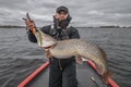 Pike fishing. Happy fisherman with big fish trophy at the boat with tackles Royalty Free Stock Photo