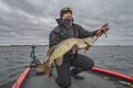 Pike fishing. Happy fisherman with big fish trophy at the boat with tackles Royalty Free Stock Photo