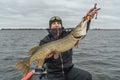 Pike fishing. Happy fisherman with big fish trophy at the boat with tackles Royalty Free Stock Photo