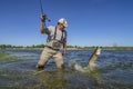 Pike fishing. Happy fisherman fights with big fish in water at river