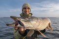 Pike fishing. Happy fisherman holding big fish at boat Royalty Free Stock Photo