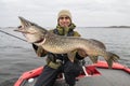 Pike fishing. Happy fisherman holding big fish at boat Royalty Free Stock Photo