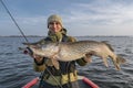 Pike fishing. Happy fisherman holding big fish at boat Royalty Free Stock Photo