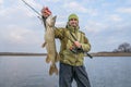 Pike fishing. Happy fisherman holding big fish and tackle Royalty Free Stock Photo