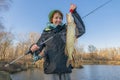 Pike fishing. Lady fisherwoman holding fish and tackle in hands