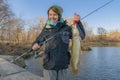 Pike fishing. Lady fisherwoman holding fish and tackle in hands