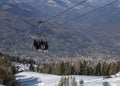 Four middle aged men skiers take a chair lift up the mountain at Pila ski resort in Aosta Valley, Italy. City of Aosta in backgrou