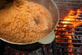 Pilaf cooking on fire outdoor. Open air kitchen at party picnic. Big pot with dish of rice and meat stays on wire rack and steams Royalty Free Stock Photo