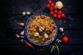 Pilaf and ingredients on plate with oriental ornament on a dark wooden background. Central-Asian cuisine - Plov Top view