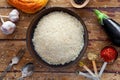 Pilaf ingredients, rice, vegetables, pita, cutlery, spices on rustic background Royalty Free Stock Photo
