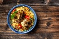 Pilaf plate with oriental ornament, wooden background, concept of oriental Uzbek cuisine, top view, copy space