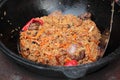 Pilaf prepare in big black cast iron with chefs hand.