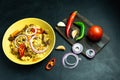 Pilaf on a yellow plate, tomatoes, garlic, peppers and onions on a dark background. A dish of Central Asian cuisine. Top view Royalty Free Stock Photo