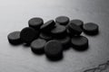 Pile of activated charcoal pills on black table, closeup. Potent sorbent