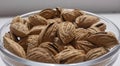 A pile of almonds in a plate close-up. Salted fresh nuts in the shell in a glass container. Royalty Free Stock Photo