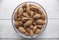 A pile of almonds in a plate close-up. Salted fresh nuts in the shell in a glass container. Top view.