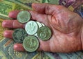 A pile of anniversary coins of republic of Bulgaria in a human`s hand over a background of banknotes