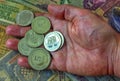 A pile of anniversary coins of republic of Bulgaria in a human`s hand over a background of banknotes