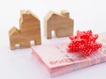 Pile of banknote with red bow and wooden house model on white background Royalty Free Stock Photo