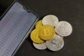 Pile of bitcoins coins next to a mobile with value tables