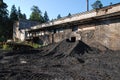 Pile of black coal pieces near the dirt gray brick wall of a building in the forest