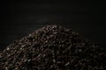 A pile of black fanning or broken loose leaf tea on a dark black background. Close-up, side view.