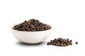 Pile of black pepper seeds and black pepper seeds in white ceramic cup isolated on white background Royalty Free Stock Photo