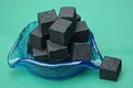 A pile of black square charcoal for a hookah in a blue glass ashtray Royalty Free Stock Photo