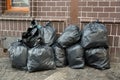 Pile of black trash bags filled with garbage near brick wall on the street Royalty Free Stock Photo