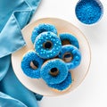 A pile of blue chocolate candy dipped donuts on a rustic plate with sprinkles.