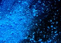 Pile of blue colored pigment powder. Blue powder particles splatter on black blackground